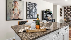 A kitchen with granite countertops, a wine bottle, and a coffee machine.