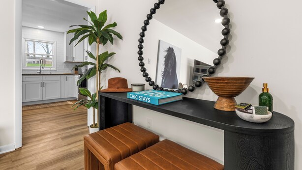 A modern kitchen with white cabinets, a black countertop, and a large mirror.