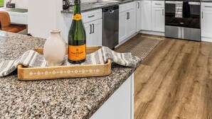 A modern kitchen with white cabinets, granite countertops, and stainless steel appliances.