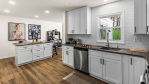 A modern kitchen with white cabinets, stainless steel appliances, and a large window.