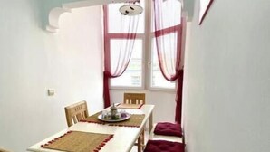 Een eethoek met een tafel, stoelen en een raam met gordijnen.