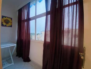 A room with a large window, a white desk, and a sunflower painting on the wall. - LE SAFRAN apartment in the center of Agadir, close to the beach. (Agadir)