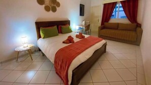 Een hotelkamer met een bed, een slaapbank, een klein tafeltje en een decoratie aan de muur.