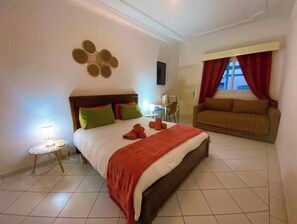 A hotel room with a bed, a sofa, a small table, and a wall decoration. - LE SAFRAN apartment in the center of Agadir, close to the beach. (Agadir)
