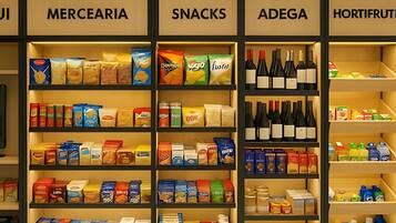 Uma loja com prateleiras identificadas como MERCERAIA, SNACKS, ADEGA e HORTIFRUTI.