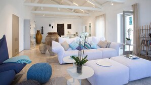 A spacious living area with a white sofa, blue ottoman, and a small white table. - TROPEA VETERA LuxuryHome-Casa Forno1638 (Tropea)
