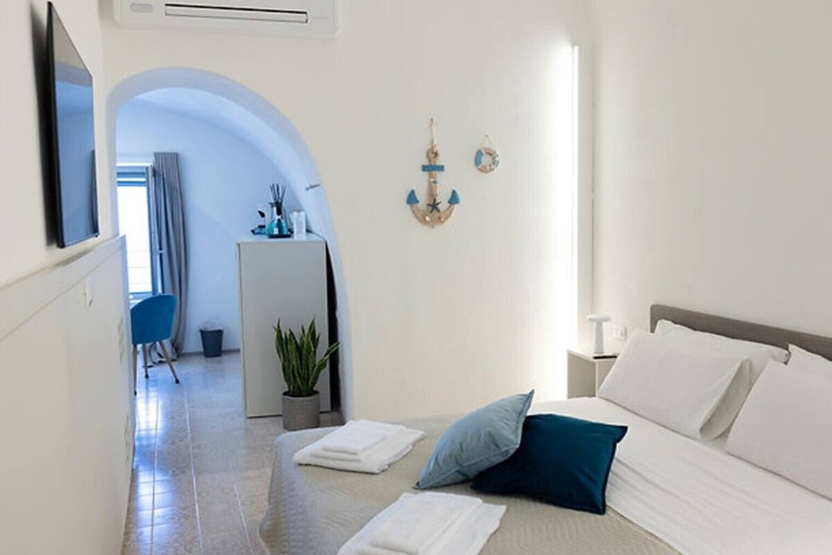 Ein Hotelzimmer mit Bett, Schreibtisch, Stuhl, Zimmerpflanze und Wanddeko.