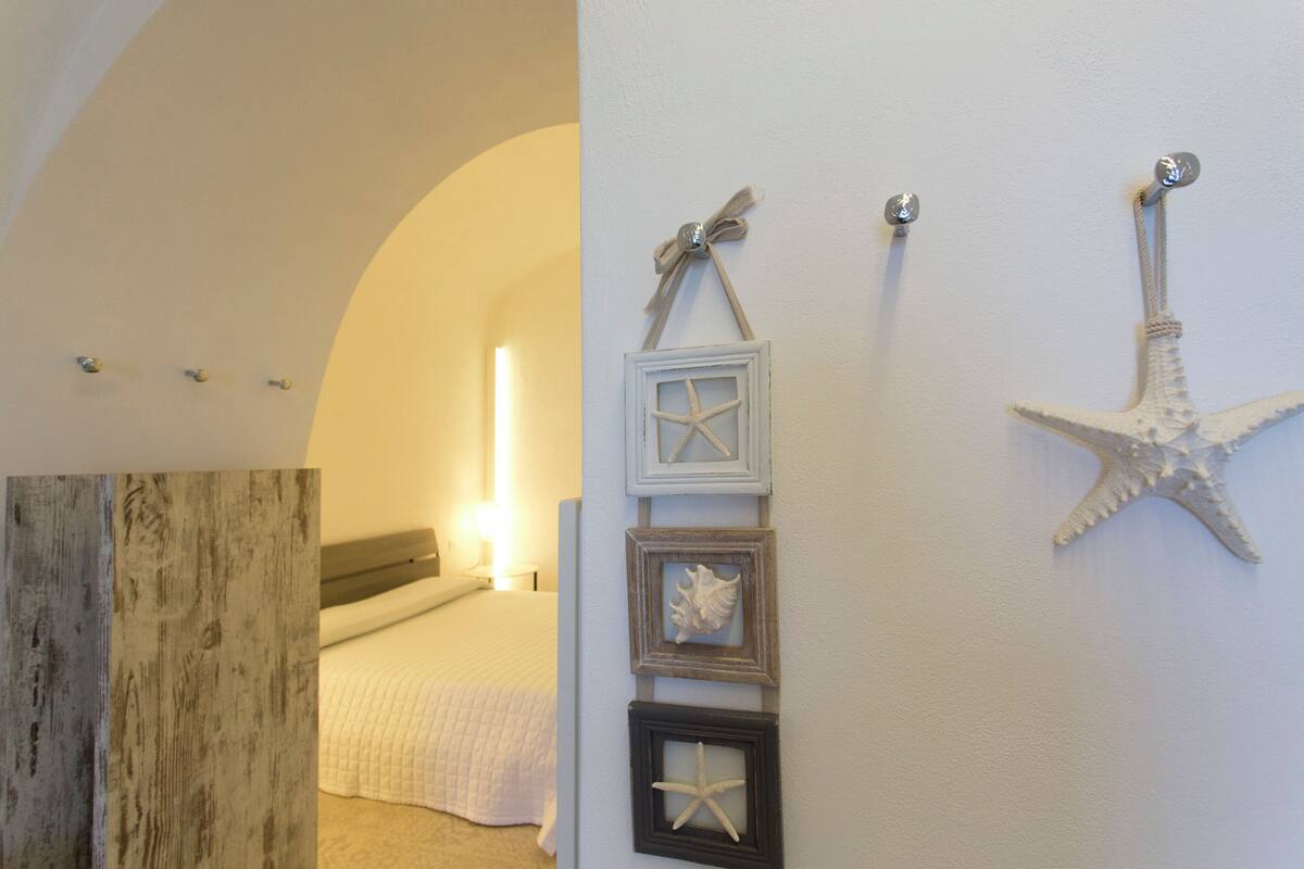 Ein Schlafzimmer mit einem Bett, einer Wanddekoration mit einem Seestern und einer Wand in Holzoptik.