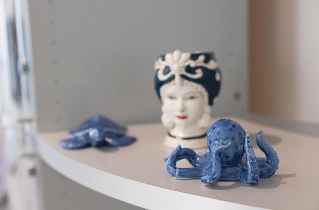A ceramic sculpture of a figure with a blue and white design on a shelf.