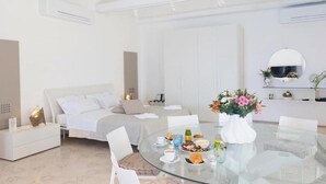 A modern hotel room with a bed, bedside table, and a breakfast table with flowers. - TROPEA VETERA LuxuryHome-Casa Forno1638 (Tropea)