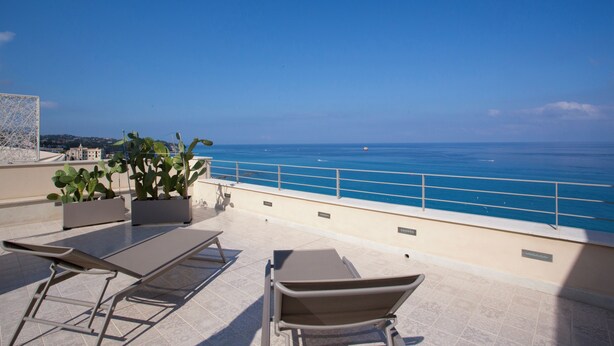 A rooftop terrace with lounge chairs, potted plants, and a view of the sea. - TROPEA VETERA LuxuryHome-Casa Forno1638 (Tropea)
