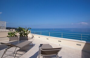 A rooftop terrace with lounge chairs, potted plants, and a view of the sea. - TROPEA VETERA LuxuryHome-Casa Forno1638 (Tropea)