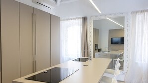 A modern kitchen with a central island, white cabinetry, and a flat-screen TV in the background. - TROPEA VETERA LuxuryHome-Casa Forno1638 (Tropea)