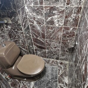 Ein Badezimmer mit Toilette, Marmorfliesen und einer Duschkabine.