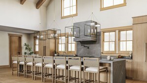 Une cuisine moderne dotée d’un îlot central, de tabourets de bar, de luminaires suspendus et de meubles de rangement en bois.