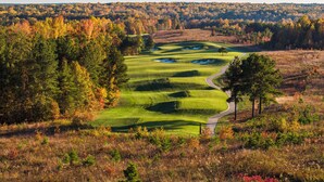 Un parcours de golf avec un sentier sinueux, entouré d’arbres aux feuilles d’automne.