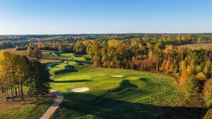 Golfkenttä, jossa on mutkitteleva polku, hiekkabunkkereita ja taustalla syksyn väreissä loistavia puita.