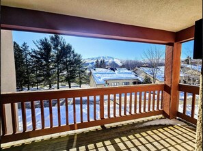 Ein Balkon mit Blick auf eine verschneite Landschaft und ein Haus.