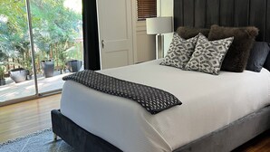 A bedroom with a bed, a ceiling fan, a window with blinds, and a view of greenery outside. - Eclectic Clarksville Austin Sauna Cold Plunge Fitness.  Walk to ACL is 1.4 miles (Austin)