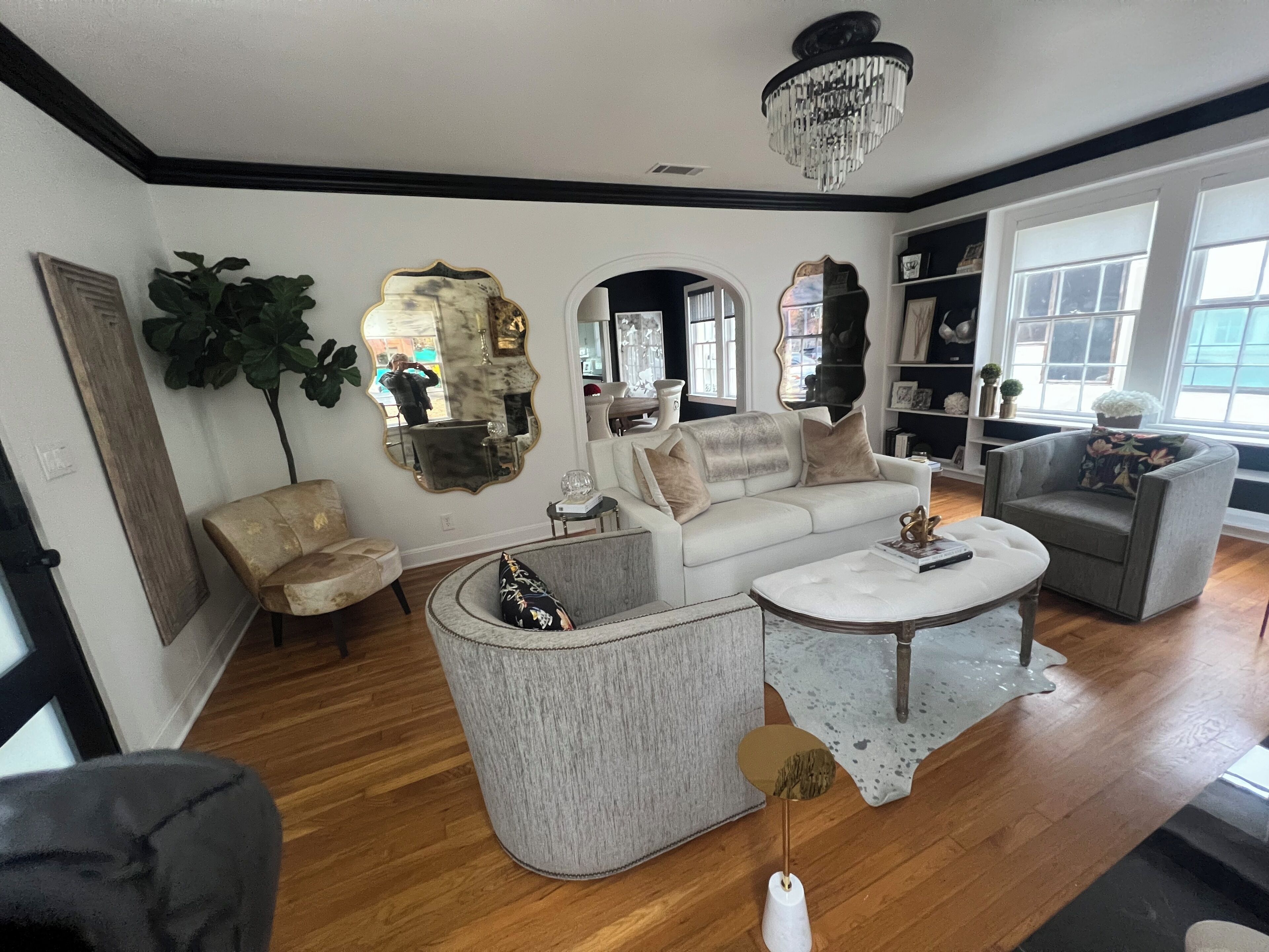 Ein Wohnzimmer mit einem weißen Sofa, einem grauen Sessel, einem runden Couchtisch und einer Kandelaberleuchte.