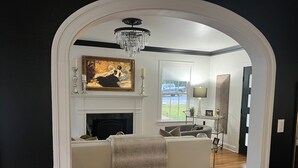 A living room with a fireplace, a sofa, a chandelier, and a painting on the wall. - Eclectic Clarksville Austin Sauna Cold Plunge Fitness.  Walk to ACL is 1.4 miles (Austin)