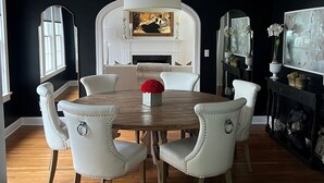 A dining area with a round wooden table, white upholstered chairs, a white fireplace, and a large mirror. - Eclectic Clarksville Austin Sauna Cold Plunge Fitness.  Walk to ACL is 1.4 miles (Austin)