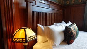 A hotel room with a wooden headboard, a bedside lamp, white bedding, and a decorative vase.