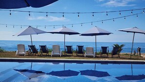 A swimming pool with chairs and umbrellas, overlooking a body of water. - Cocolisso Cabaña (El Rebalse)