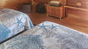 A wooden cabin room with two beds, a fan, a small table, and a television. - Cocolisso Cabaña (El Rebalse)