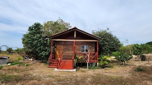 A wooden cabin with a porch, surrounded by trees and dry grass. - Cocolisso Cabaña (El Rebalse)