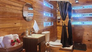 A wooden cabin bathroom with a sink, toilet, and shower curtain. - Cocolisso Cabaña (El Rebalse)