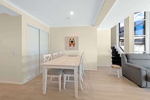 Una sala de estar moderna con una mesa de comedor, un sofá gris y una escalera que conduce a un piso superior.