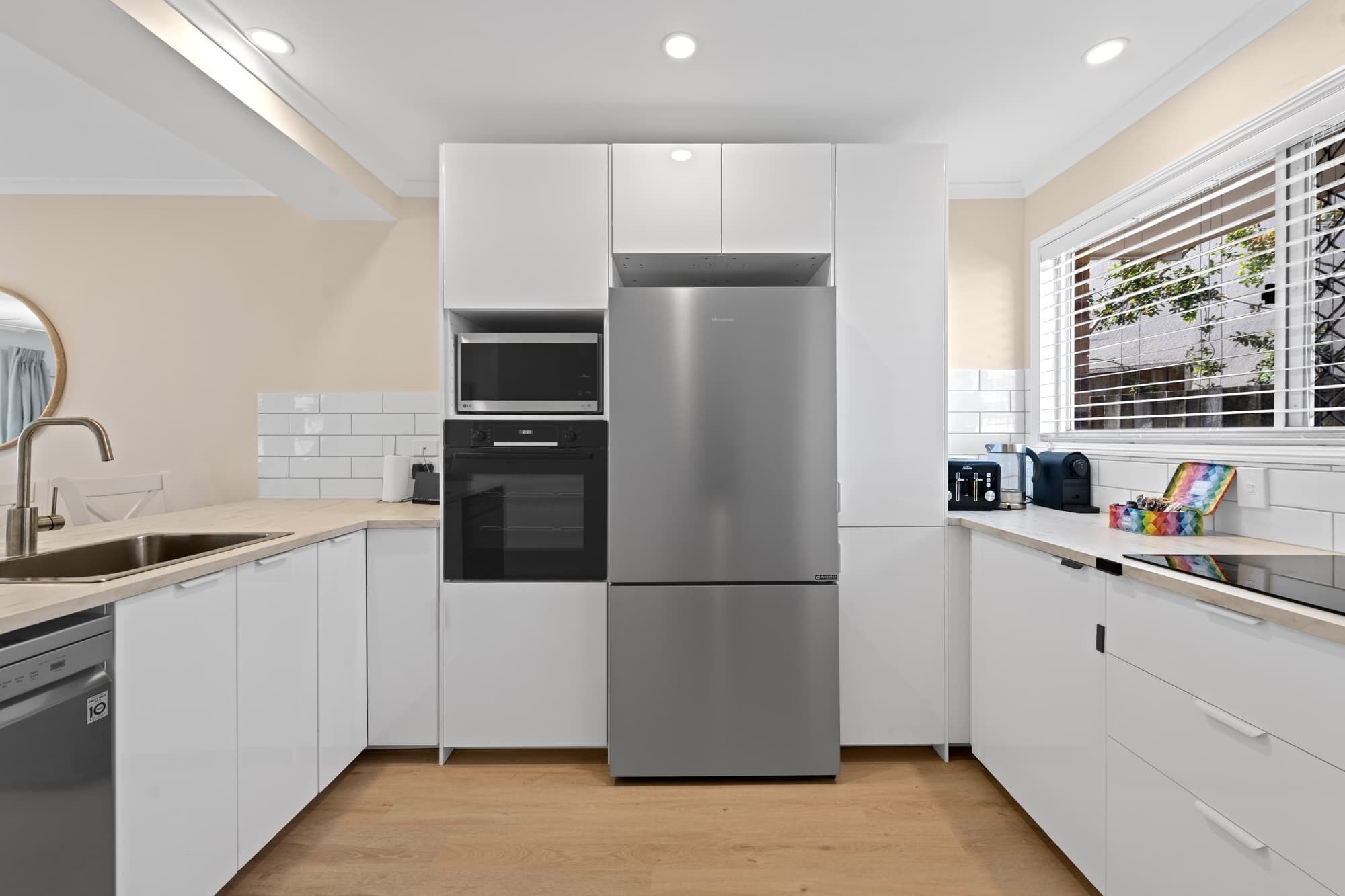 Eine moderne Küche mit weißen Schränken, einem Edelstahlkühlschrank, einer Mikrowelle und einem Toaster.