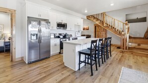 Una cocina moderna con armarios blancos, electrodomésticos de acero inoxidable y una escalera de madera.