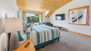 Un dormitorio con cama, mesita de noche, lámpara y televisor montado en la pared.
