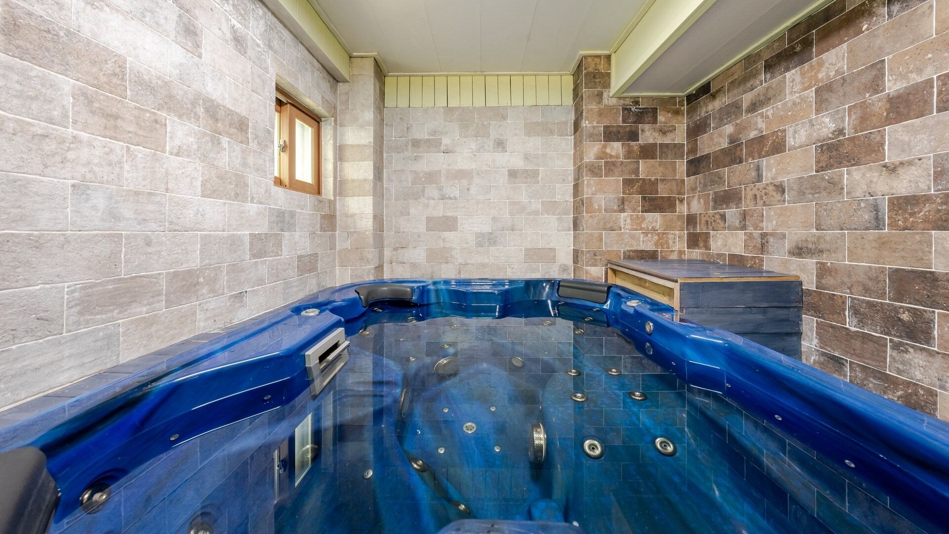 Un jacuzzi en una habitación con paredes de baldosas y un ventanal.