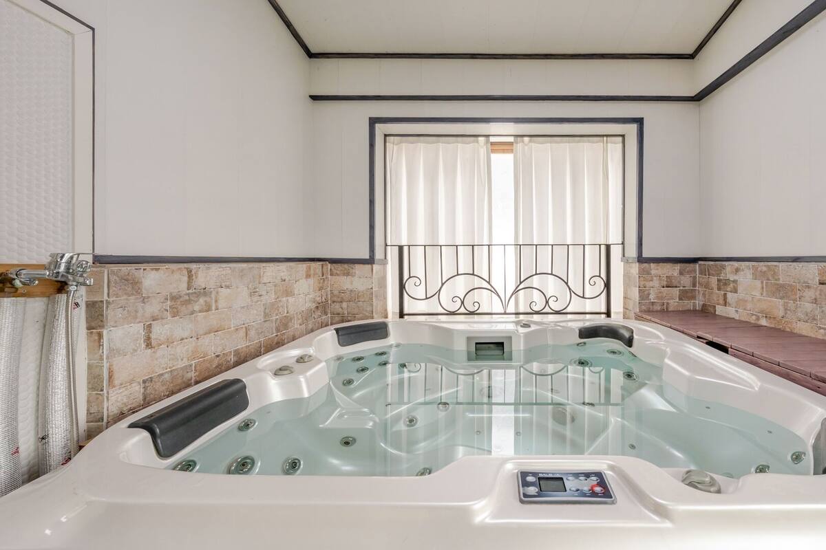 Ein Spa-Raum mit Whirlpool, Steinwand und einem Vorhangfenster.