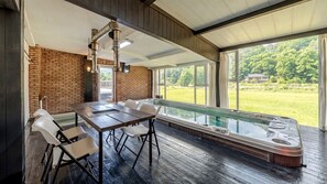 A hot tub area with a table and chairs, a brick wall, and a view of a green landscape. - Goesan Glam House Pet Pension (Goesan)