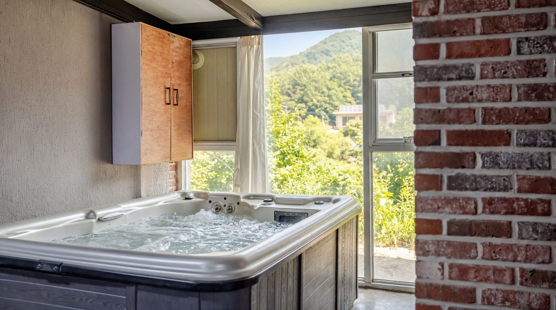 A spa area with a hot tub, wooden cabinets, and a view of a green landscape through a large window.