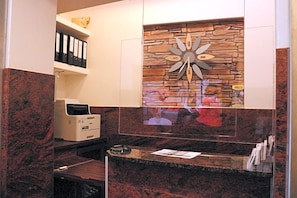 Zona de recepción con pared de piedra, un reloj e impresora.