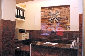 Zona de recepción con pared de piedra, un reloj e impresora.