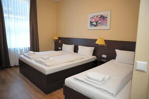 Habitación de hotel con dos camas, cabecero, un cuadro en la pared y una ventana con cortinas.