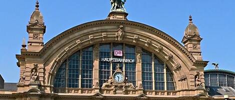 A historic building with a large clock, ornate sculptures, and a sign reading 'DB Hauptbahnhof'.