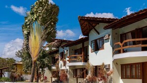 A resort with a swimming pool, a palm tree, and a two-story building with balconies. - Vila Mundaí – Peace and quiet, 500m from the beach. (Porto Seguro)