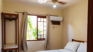 A bedroom with a bed, a ceiling fan, a window with curtains, and an air conditioning unit. - Vila Mundaí – Peace and quiet, 500m from the beach. (Porto Seguro)
