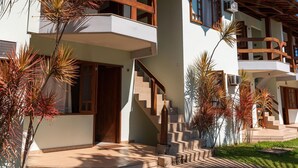 A two-story building with a balcony, a staircase, and a well-maintained lawn. - Vila Mundaí – Peace and quiet, 500m from the beach. (Porto Seguro)