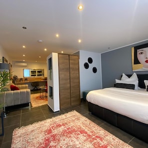 A modern bedroom with a large bed, a desk, and a sofa. - Marram Suitehotel (Münster)