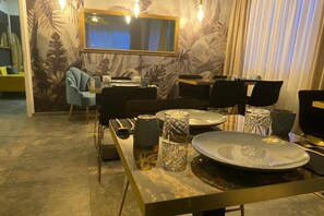 A dining area with a long table, chairs, and a mirror above. - Marram Suitehotel (Münster)