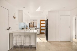 A modern kitchen with a central island, bar stools, a built-in oven, and a refrigerator.