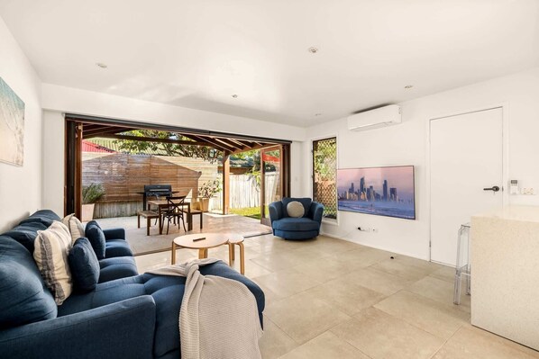 A modern living room with a sofa, a TV, and a patio area with a grill.